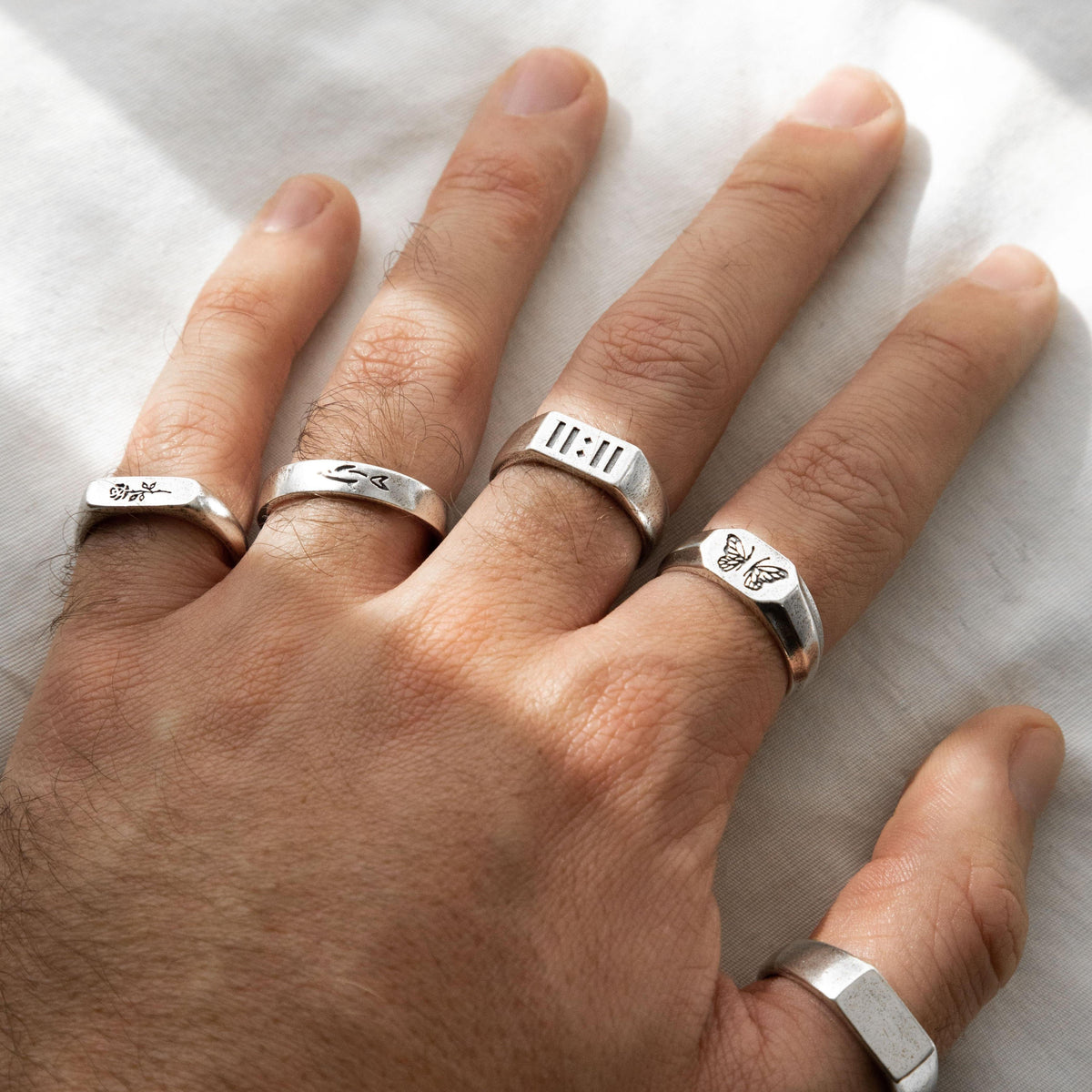 A hand with four different Billie Jo rings, including the Revival Ring, showcasing how to stack and layer the brand's sterling silver jewellery.
