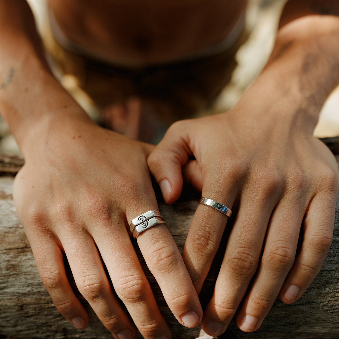 A man's hands resting on a wooden surface, wearing the sterling silver Connection Stackers from Billie Jo. Men's jewellery for everyday wear.