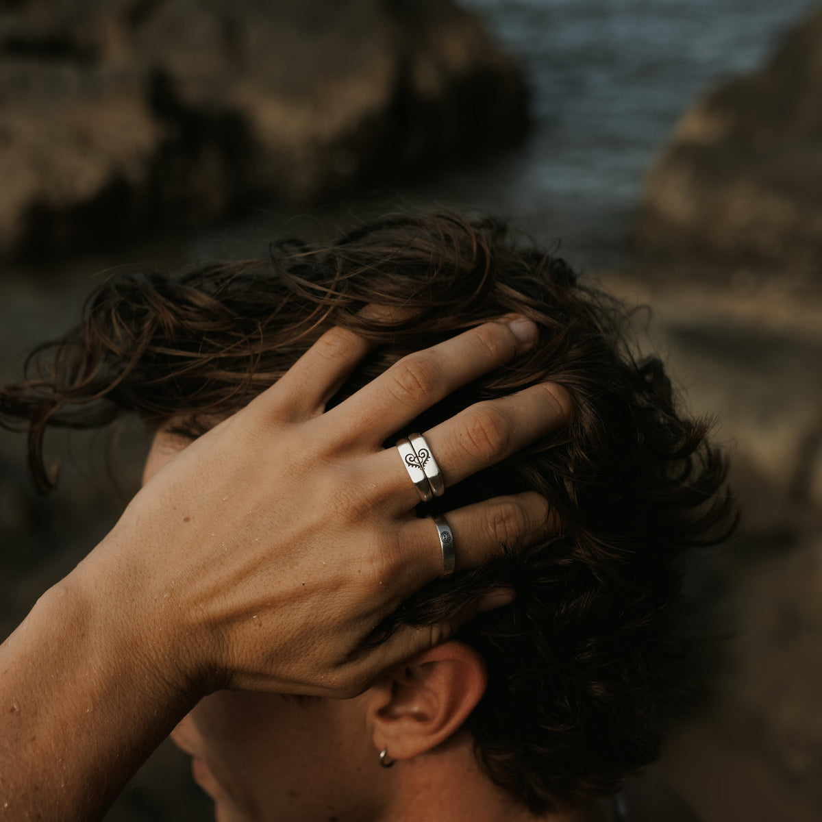 Close-up of a man's hand with the sterling silver Connection Stackers by Billie Jo, showcasing the engraved details. Modern, masculine jewellery.