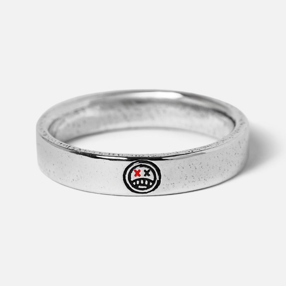 A different angle of the sterling silver Reflection Ring by Billie Jo, showcasing the detailed smiley face engraving with red 'X' eyes on the band.