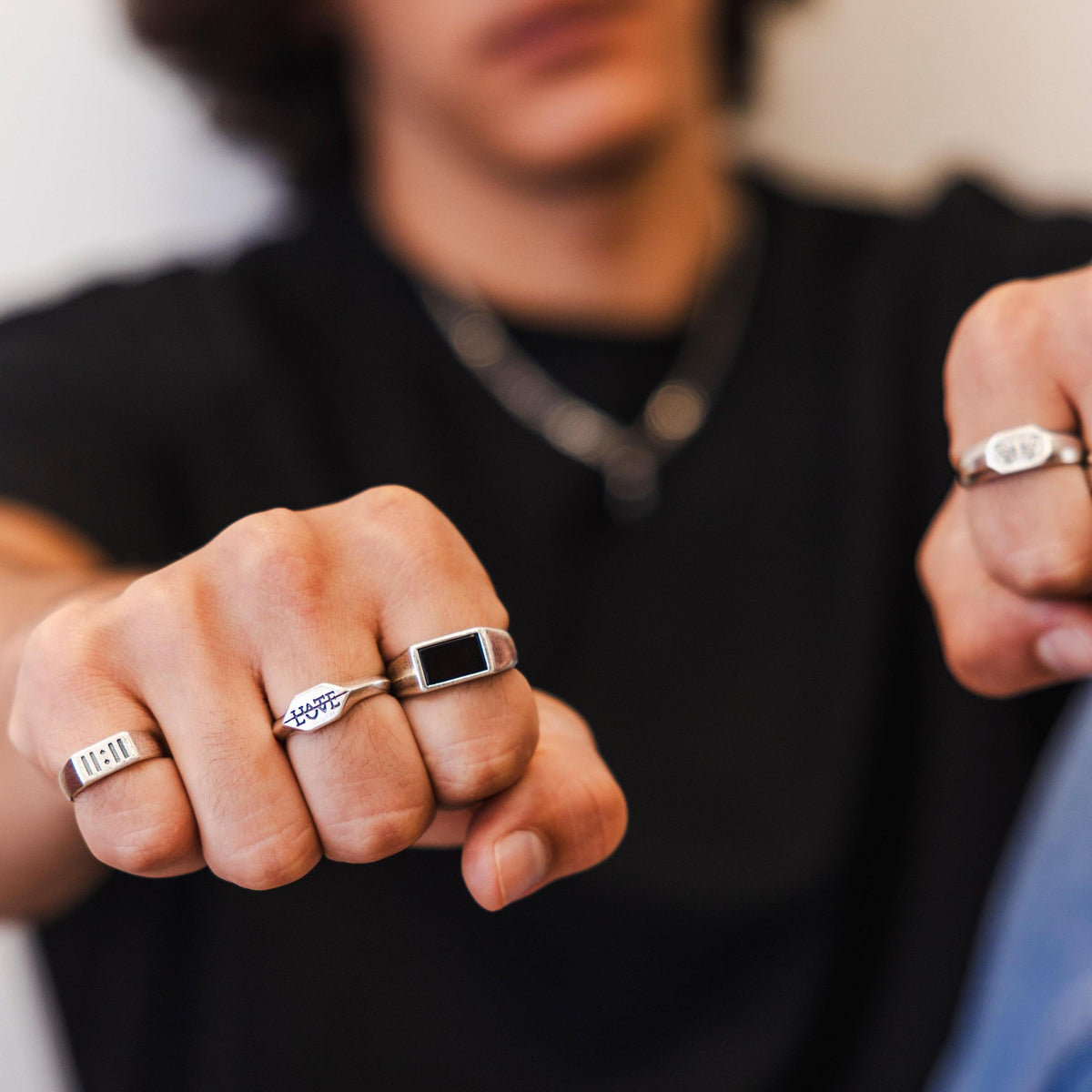 A man wearing the sterling silver Onyx Ring from Billie Jo, shown with other rings on his fists.