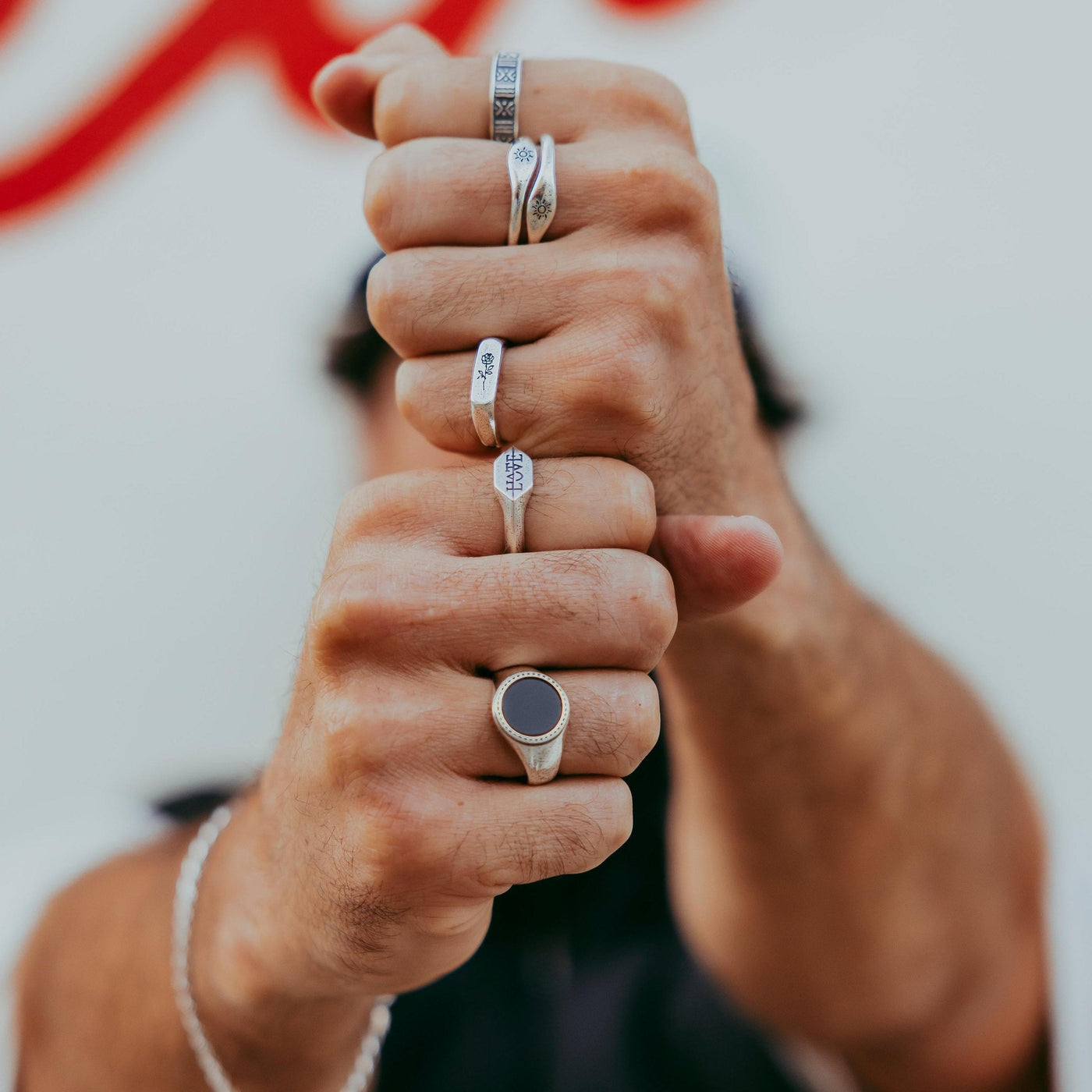 A man's fists stacked, adorned with a variety of silver rings from Billie Jo. The Rosa II ring is on the middle finger, part of a stylish, layered jewellery look.