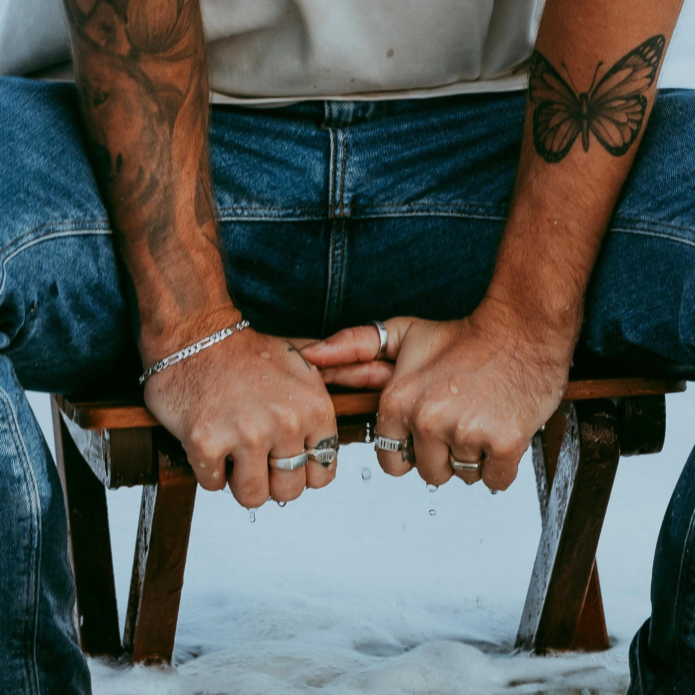 A tattooed man wearing multiple sterling silver rings, including the Momento Ring by Billie Jo, creating a modern, masculine look. An example of Australian men's jewellery.