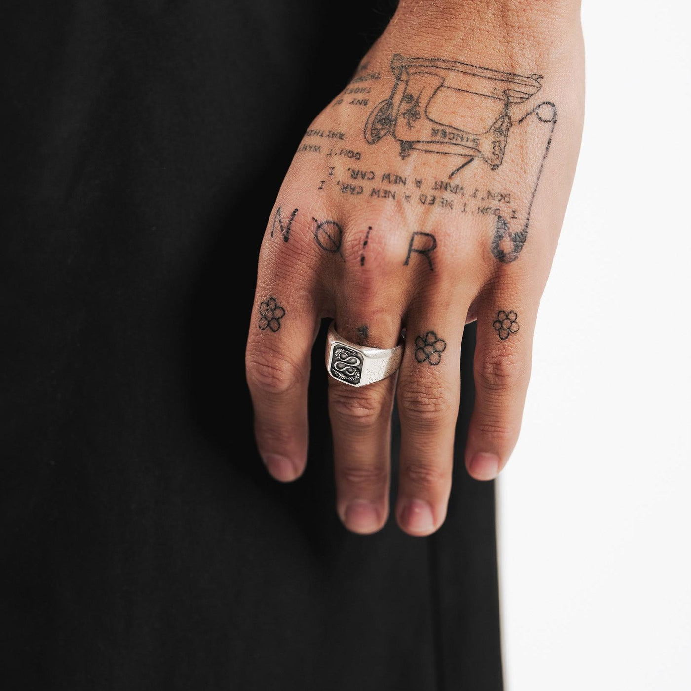 The Billie Jo Serpent Ring worn on the hand of a man with intricate tattoos, showcasing its bold and edgy style against a dark backdrop.