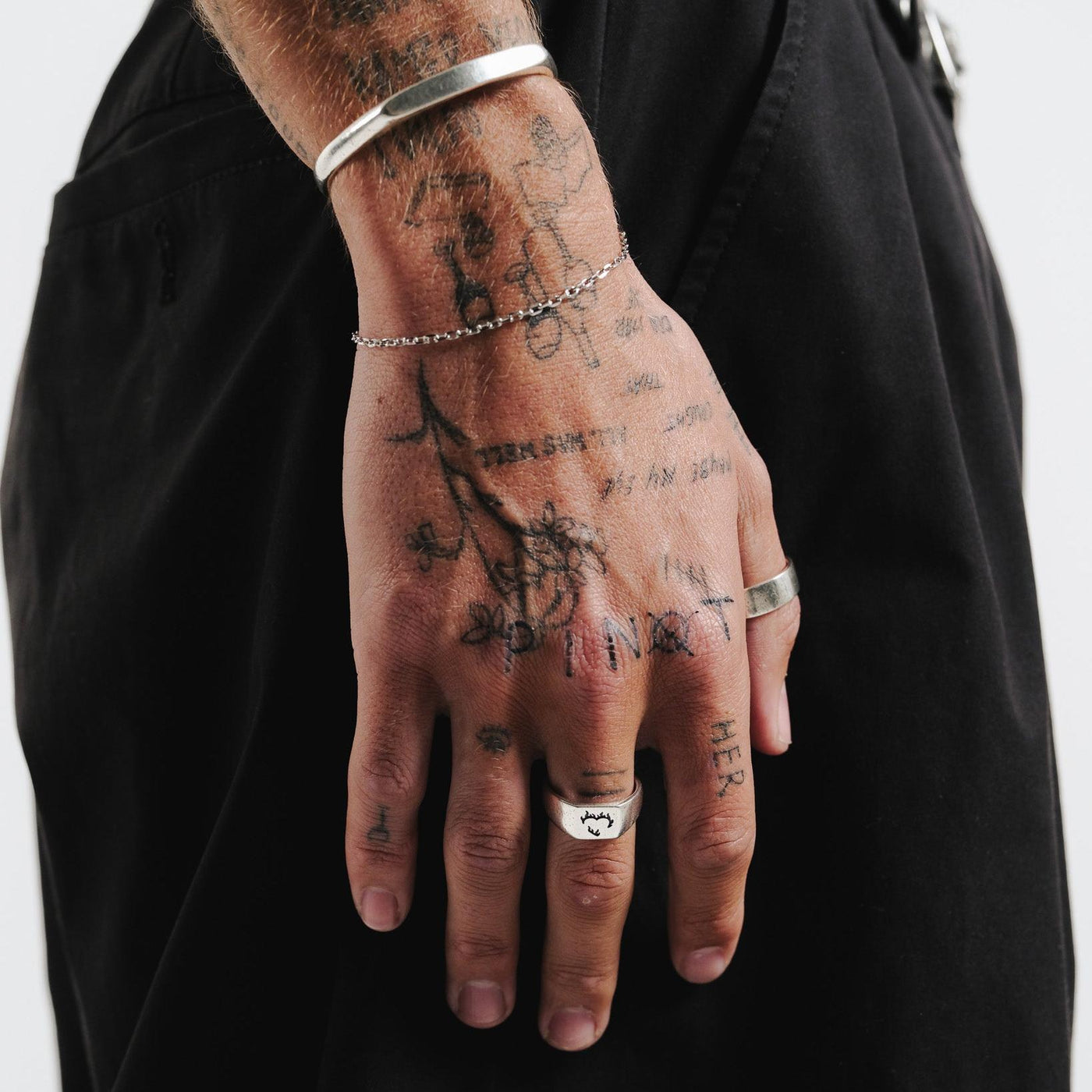 The Ember Ring by Billie Jo, a sterling silver signet ring, shown on a man's hand with tattoos and other silver jewellery for a complete look.