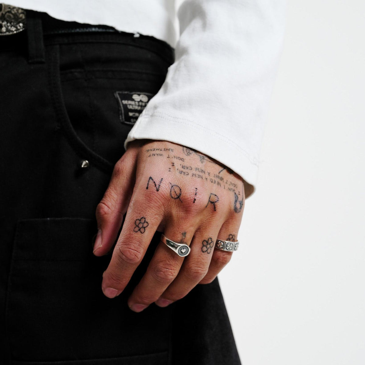 A close-up on-hand shot of the Vita Ring from Billie Jo, worn on the ring finger. The image highlights the ring's detailed design against a backdrop of black pants and a white long-sleeved shirt.
