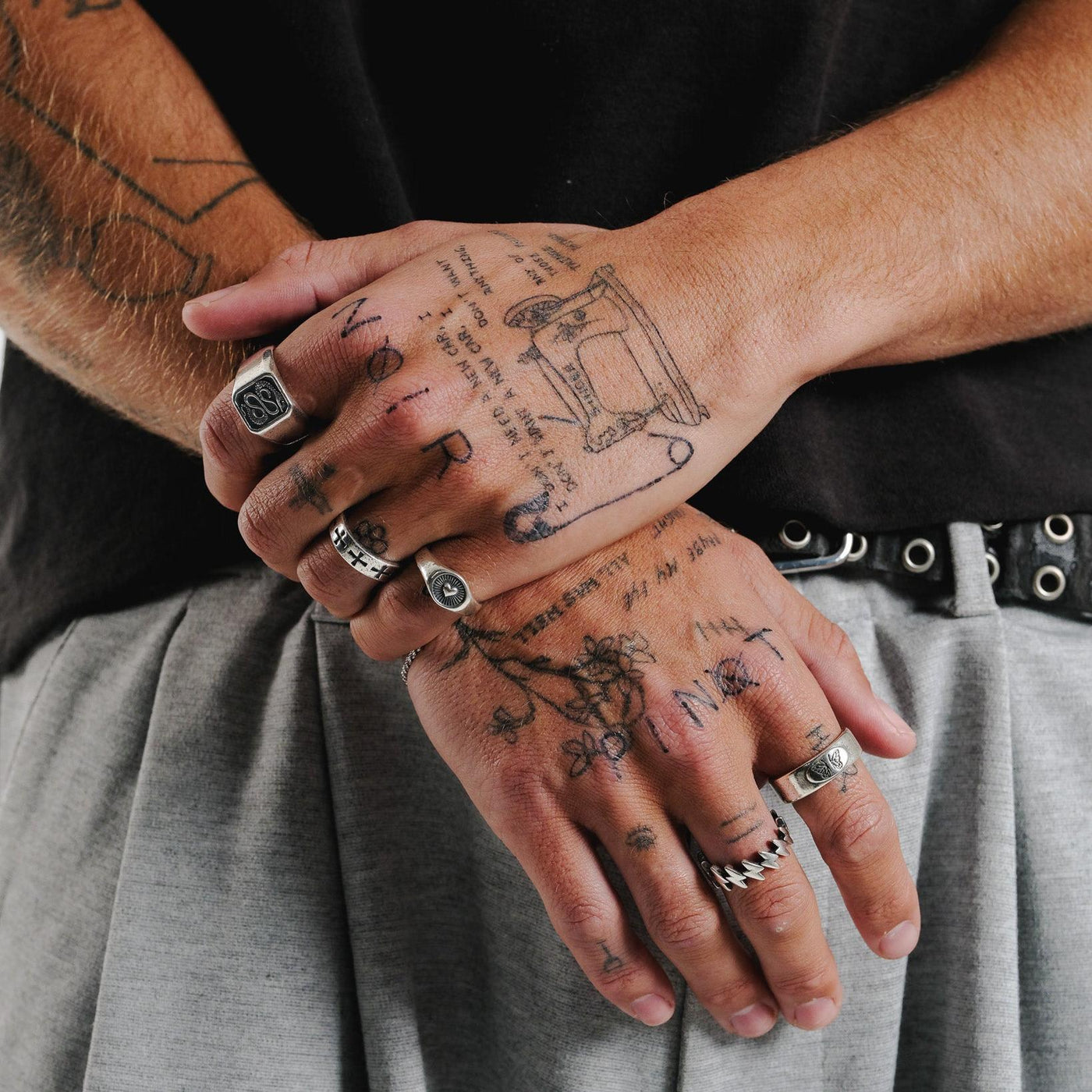 A model with tattooed hands wearing the Billie Jo Surge Ring. This image highlights the ring's unique design in a stylish context.