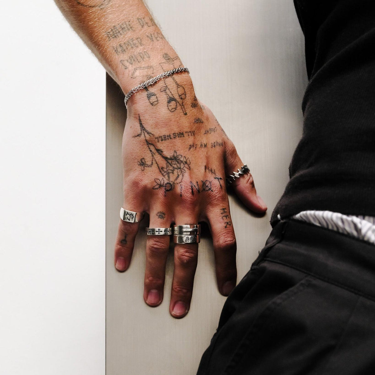 A man's hand adorned with several sterling silver rings, including the distinctive Ember Ring by Billie Jo, against a white background.