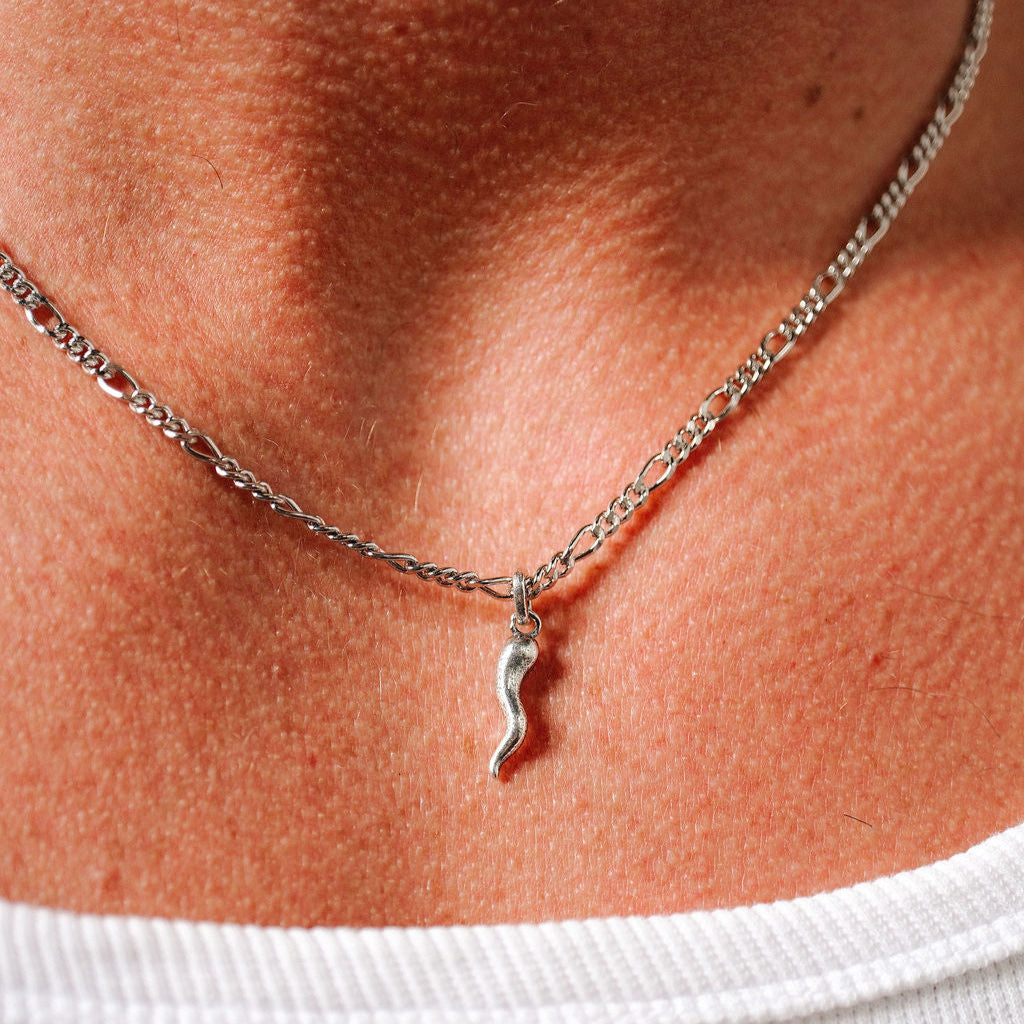 Close-up of the sterling silver Chilli Pendant by Billie Jo, showing the texture of the charm and the detail of the figaro chain against the wearer's skin.