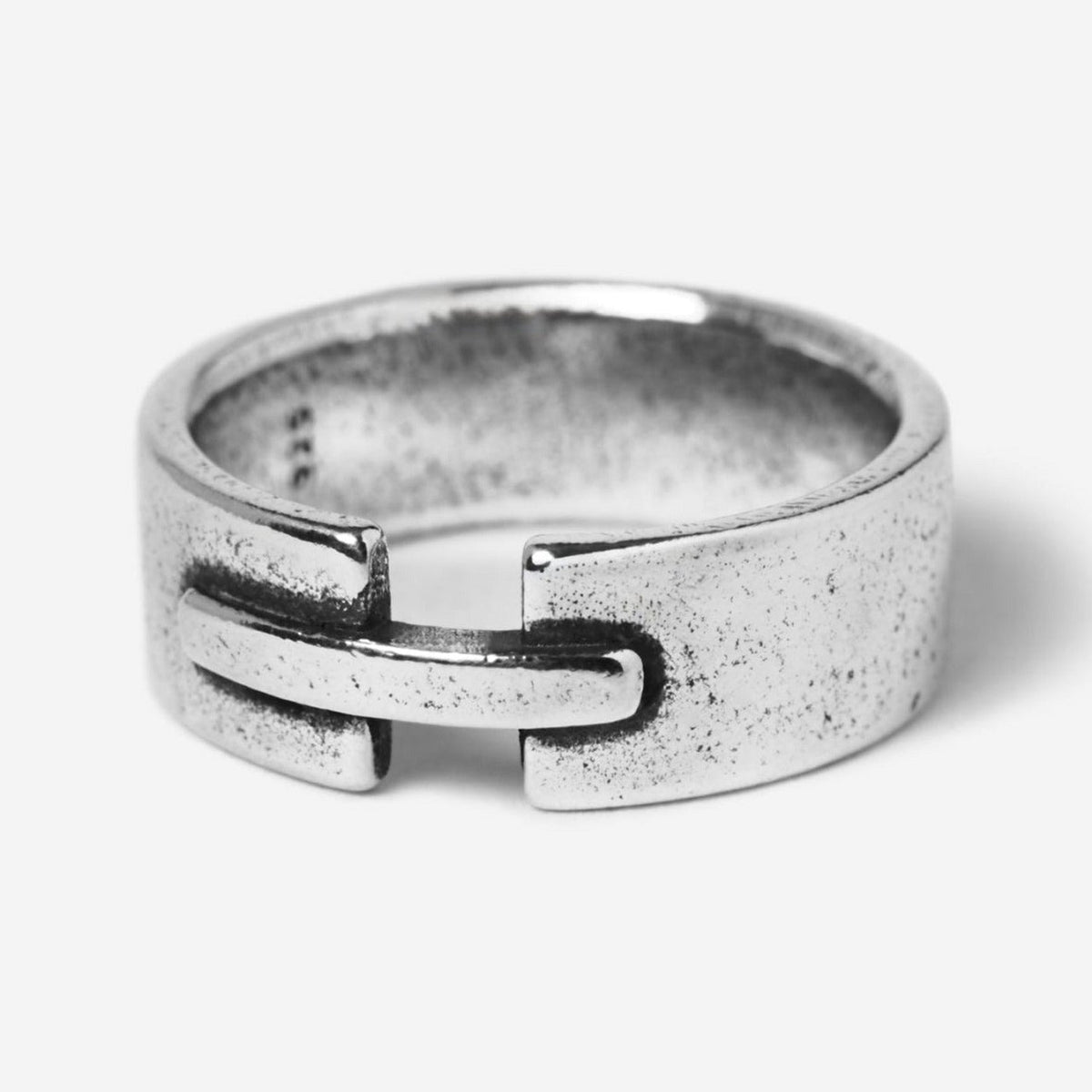 A studio shot of the Billie Jo Bind Ring in 925 sterling silver. The men's ring has a unique, industrial-inspired design with an interlocking clasp detail and a brushed, weathered finish.