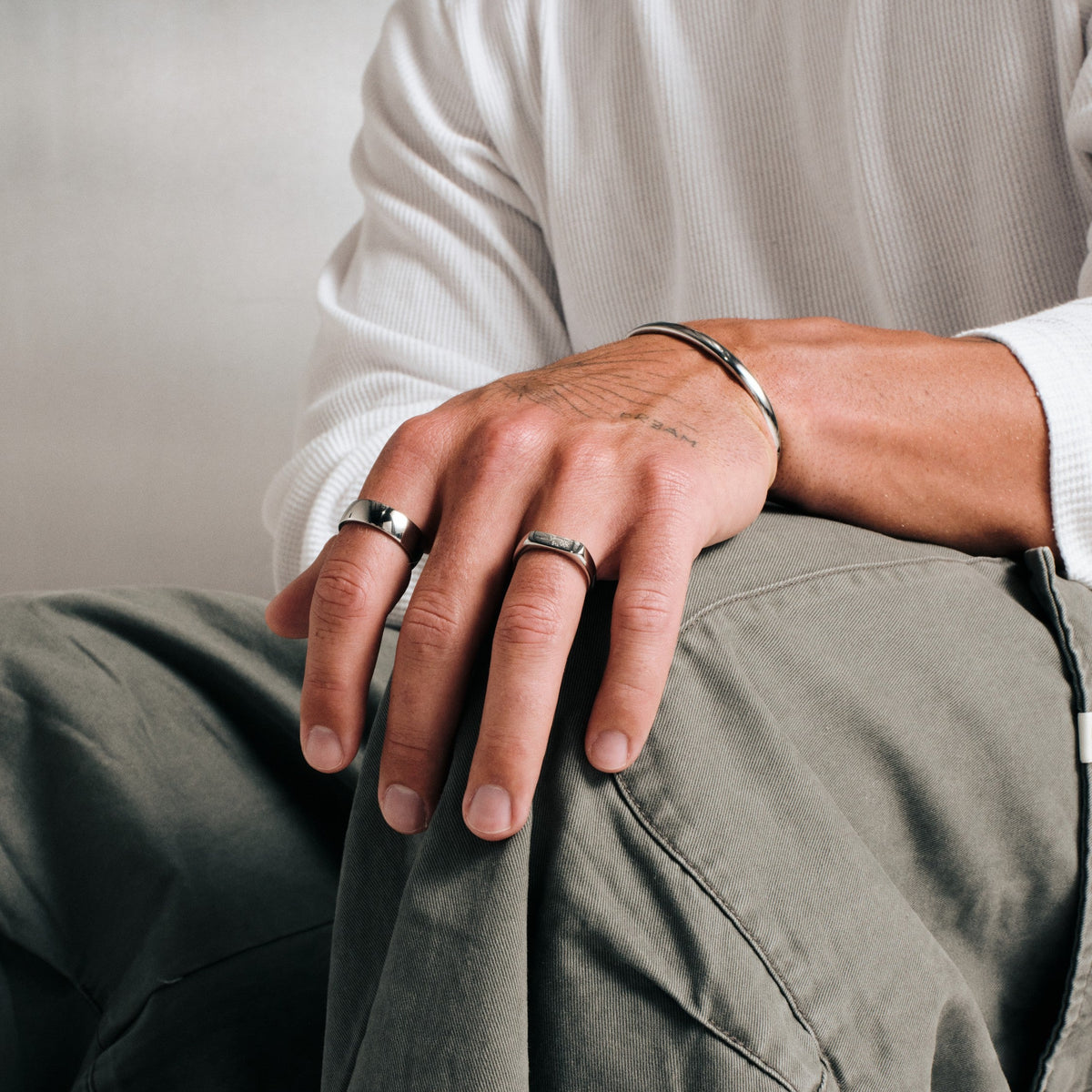 Men's Canvas Ring in 316L stainless steel, silver finish, worn on the index finger, seated, hand resting on his knee