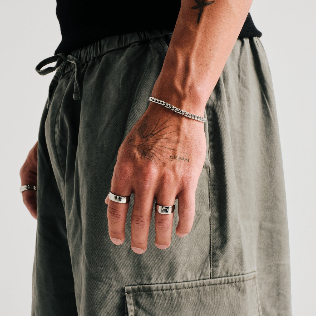 Men's Ember Ring in 316L stainless steel, silver finish, worn on his left index finger, hand hanging by his side