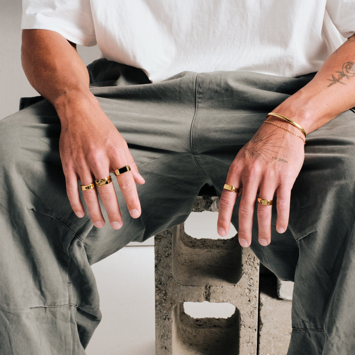Men's Gold Forge Ring in 18k gold infused stainless steel, worn on the ring finger, white tee, olive pants