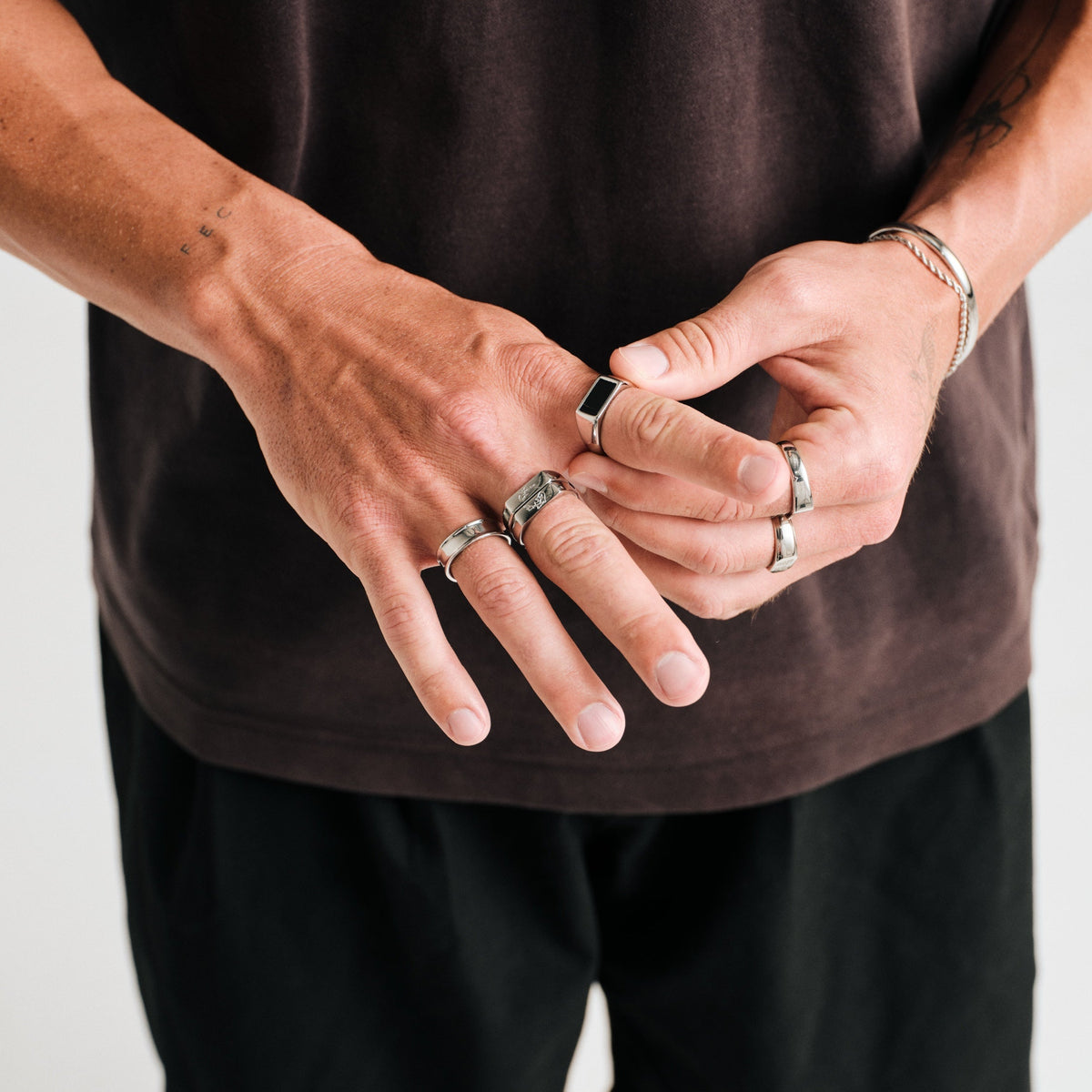 Men's Forge Ring in 316L stainless steel, silver finish, worn on the ring finger, hands together at the waist
