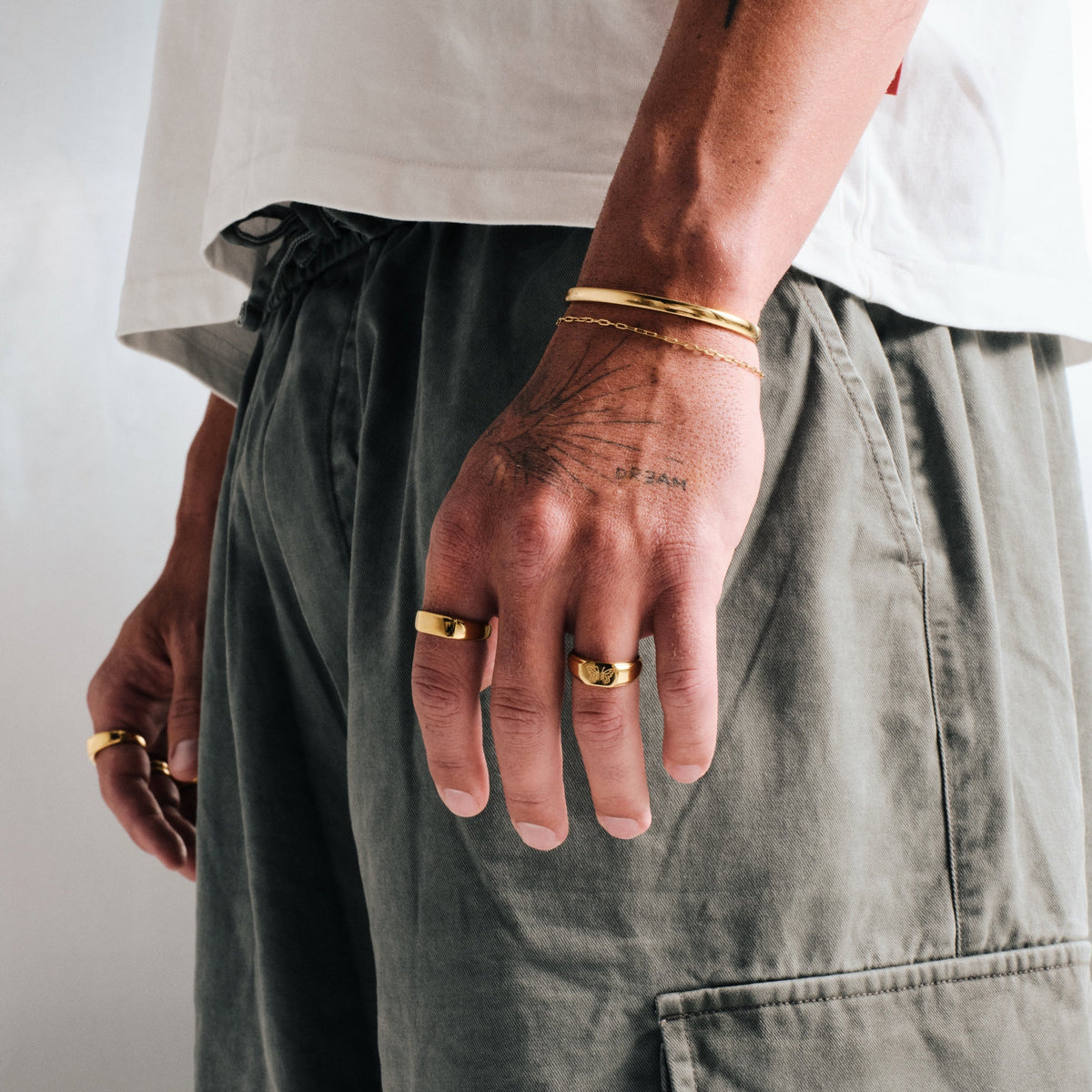 Men's Gold Genesis Ring in 18k gold infused stainless steel, worn on his left index finger, hand by his pocket