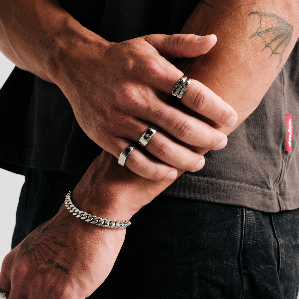 Men's Genesis Ring in 316L stainless steel, silver finish, in a stack, right hand resting over left forearm