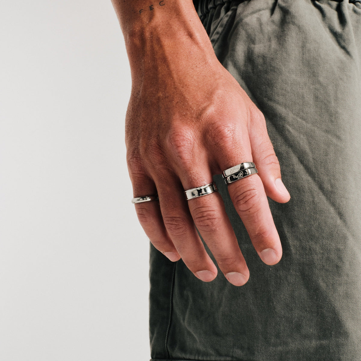 Men's Koi Stackers in 316L stainless steel, silver finish, both worn on his right index finger, olive pants