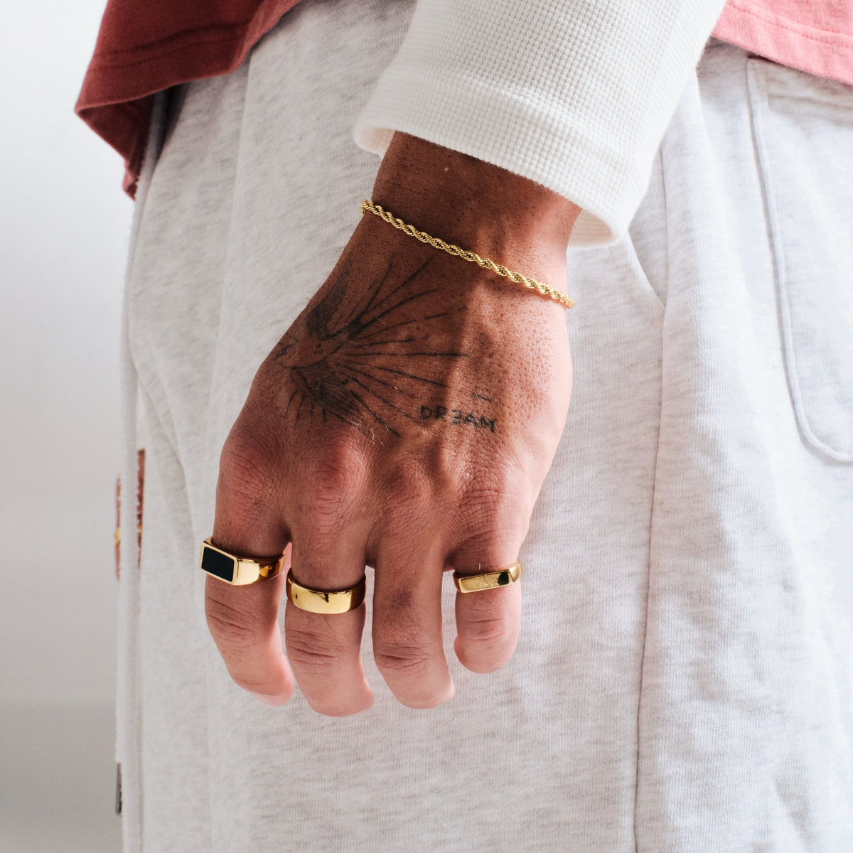 Men's Gold Onyx Ring in 18k gold infused stainless steel, worn on his left index finger, hand by his side