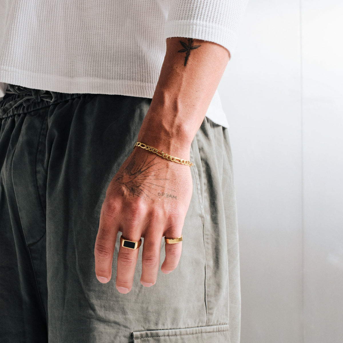 Men's Gold Onyx Ring in 18k gold infused stainless steel, worn on his left middle finger, hand by his side