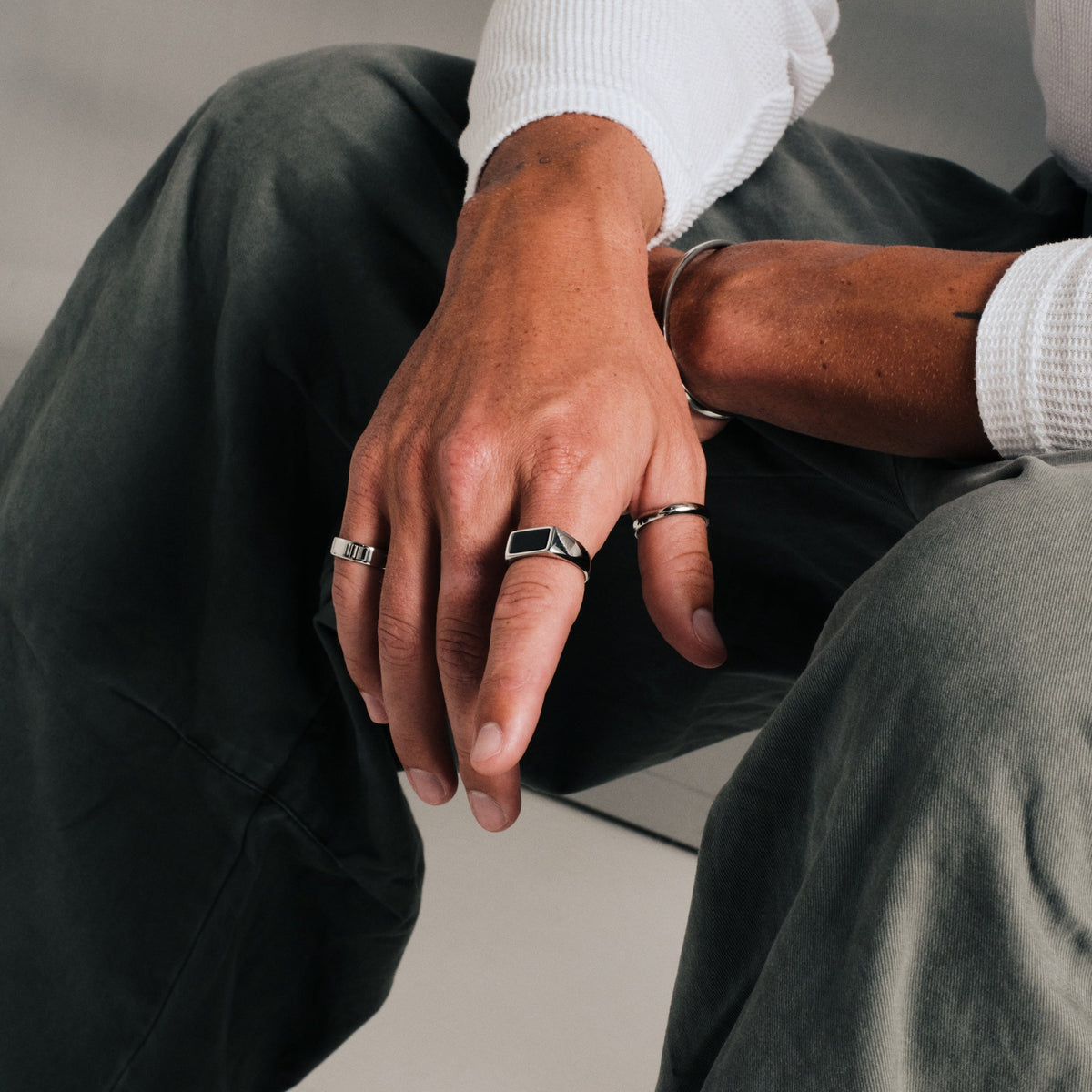Men's Onyx Ring in 316L stainless steel, silver finish, in a stack, seated, hand hanging over his knee