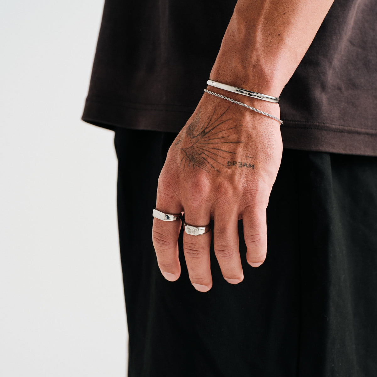 Men's Revival Ring in 316L stainless steel, silver finish, worn on his left middle finger, hand hanging at his side