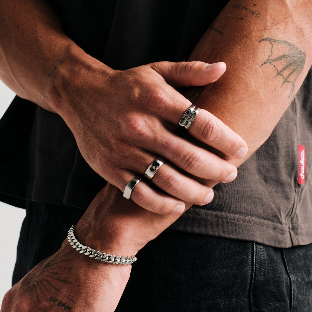Men's Rosa Stackers in 316L stainless steel, silver finish, worn on his right index finger, arms crossed