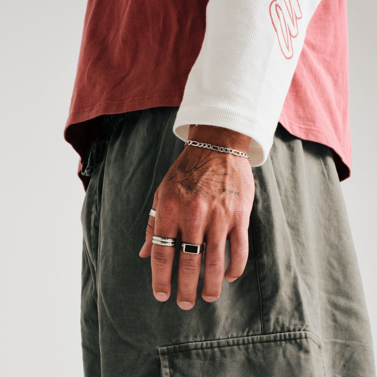 Men's Stacker Rings in 316L stainless steel, silver finish, both worn on his left index finger, hand relaxed at his side