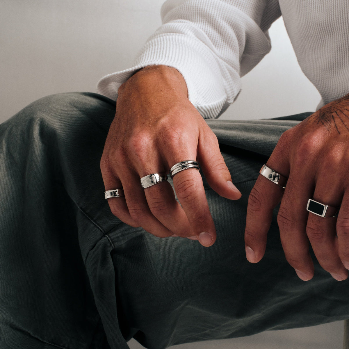Men's Stacker Rings in 316L stainless steel, silver finish, both worn on his right index finger, seated, hands over his knee