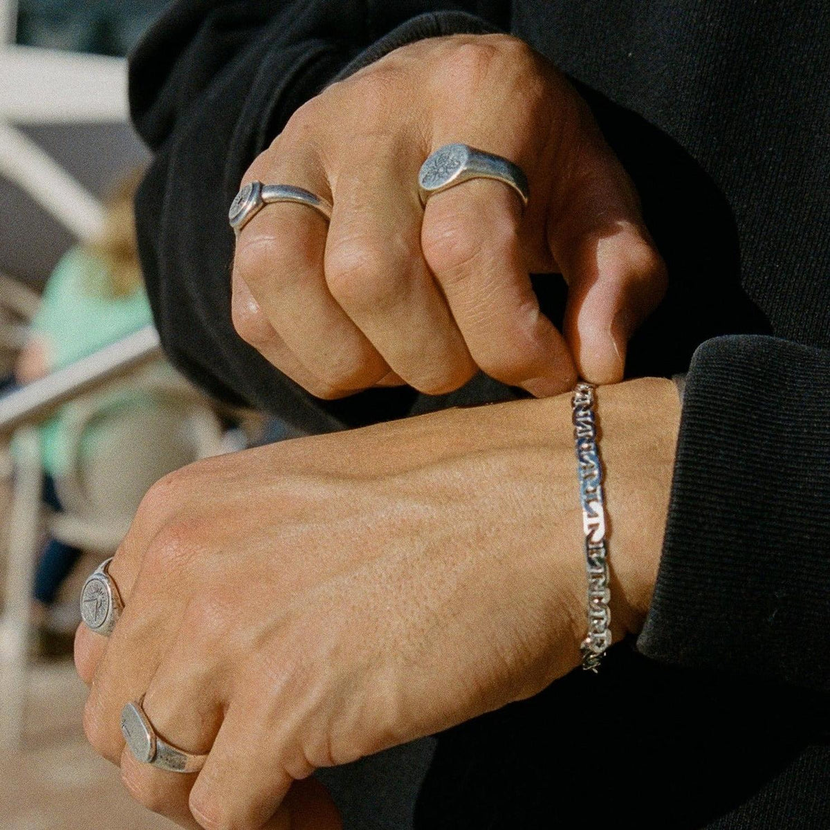 A close-up of a man's hands as he fastens the clasp of the sterling silver Mariner Bracelet from Billie Jo, highlighting the bracelet's detail.