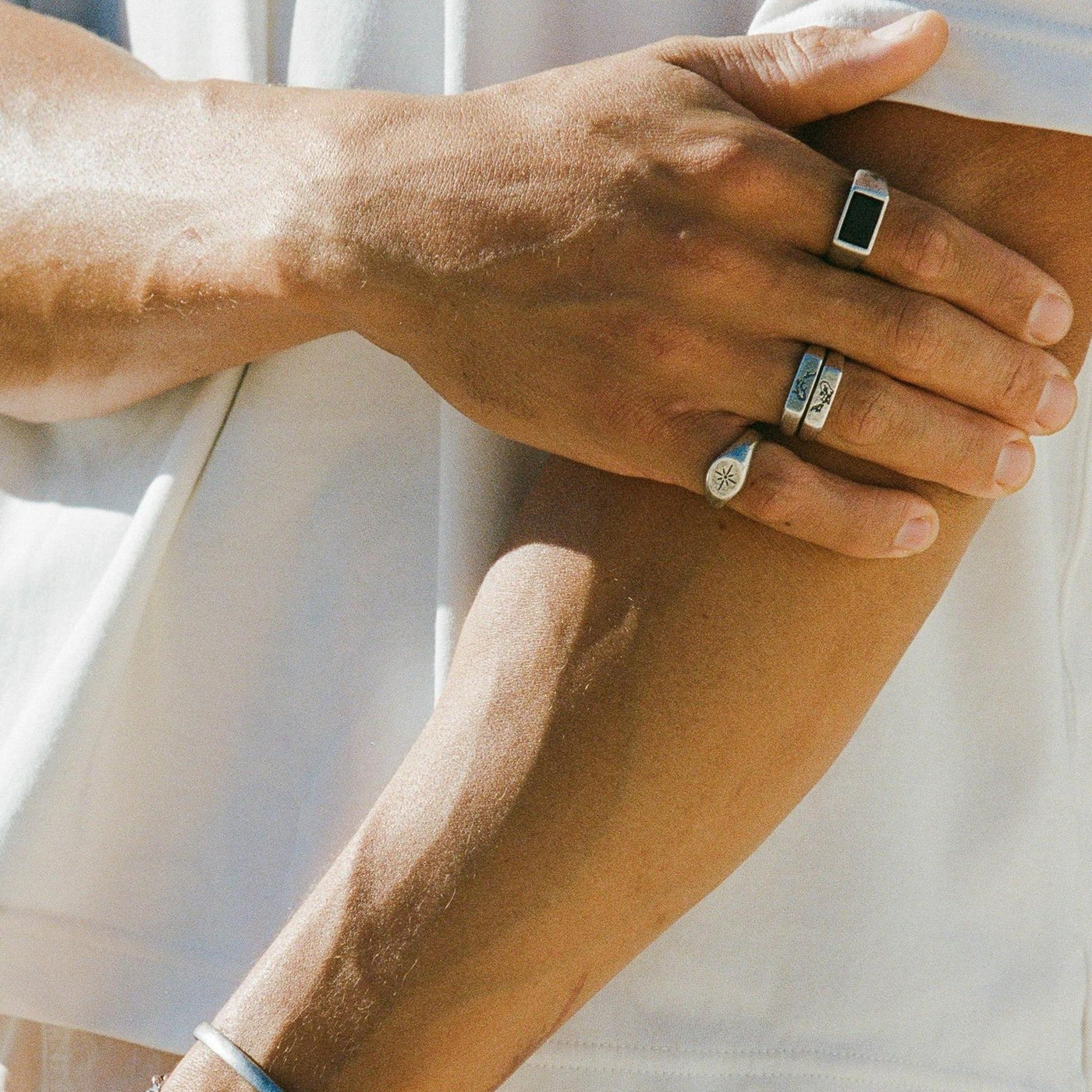 A detailed on-hand shot of the men's Luminous Ring in sterling silver by Billie Jo. The starburst engraving and textured band are clearly visible. Modern men's jewellery.