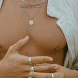 A close-up of a man's chest, showing the sterling silver Untold Pendant from Billie Jo layered with a thicker chain for a modern, stylish look.