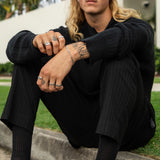 A male model with tattoos wears the Billie Jo Figaro Bracelet with an all-black outfit. This lifestyle shot shows how the sterling silver bracelet adds a point of interest to a dark, modern look.