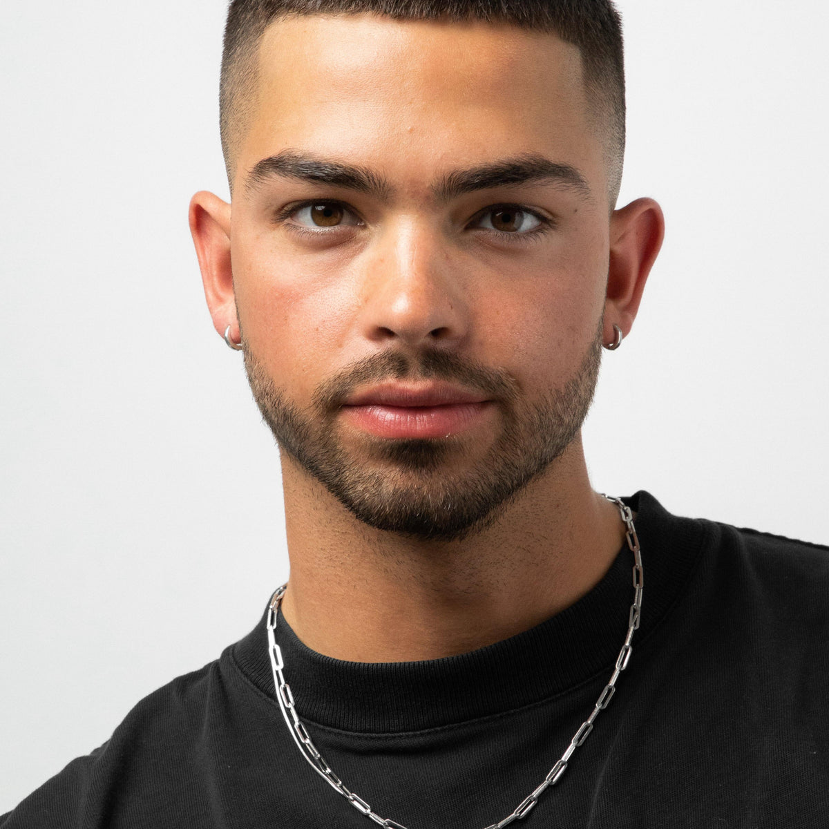 A striking portrait of a male model wearing the sterling silver Billie Jo Lumina hoop earrings, which complement his modern, minimalist style.