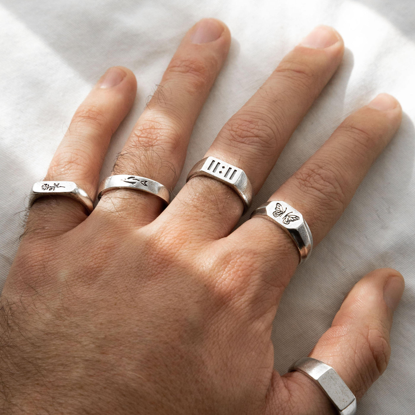 A hand with four different Billie Jo rings, including the Revival Ring, showcasing how to stack and layer the brand's sterling silver jewellery.