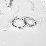 A creative shot of two sterling silver Prowess Rings from Australian brand Billie Jo, with water splashing over them on a clean white surface, highlighting their durability.