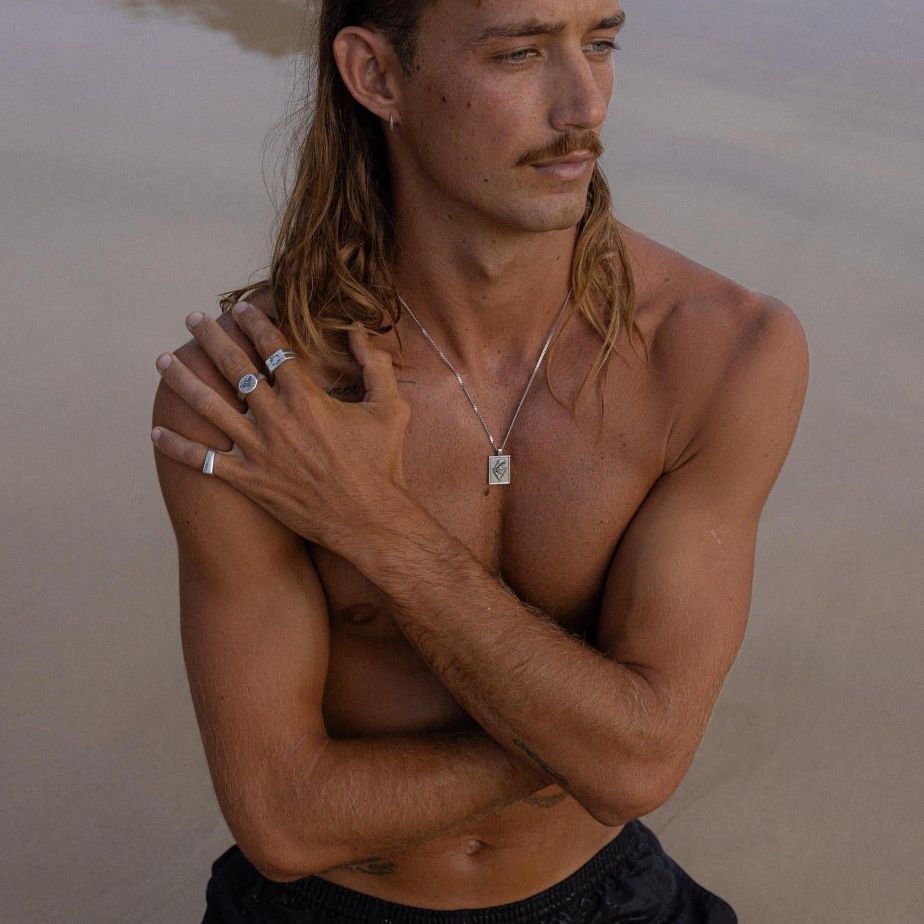 A side profile of a man wearing the Burleigh Pendant, with the sterling silver chain and pendant visible. From Australian men's jewellery brand Billie Jo.
