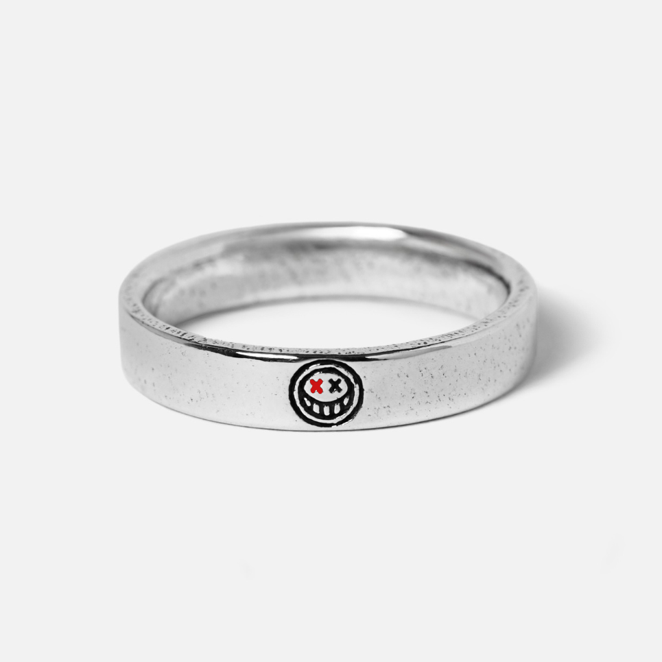 A sterling silver Reflection Ring from Billie Jo, featuring a unique engraved smiley face with red 'X' eyes. This men's ring has a modern, minimalist style.