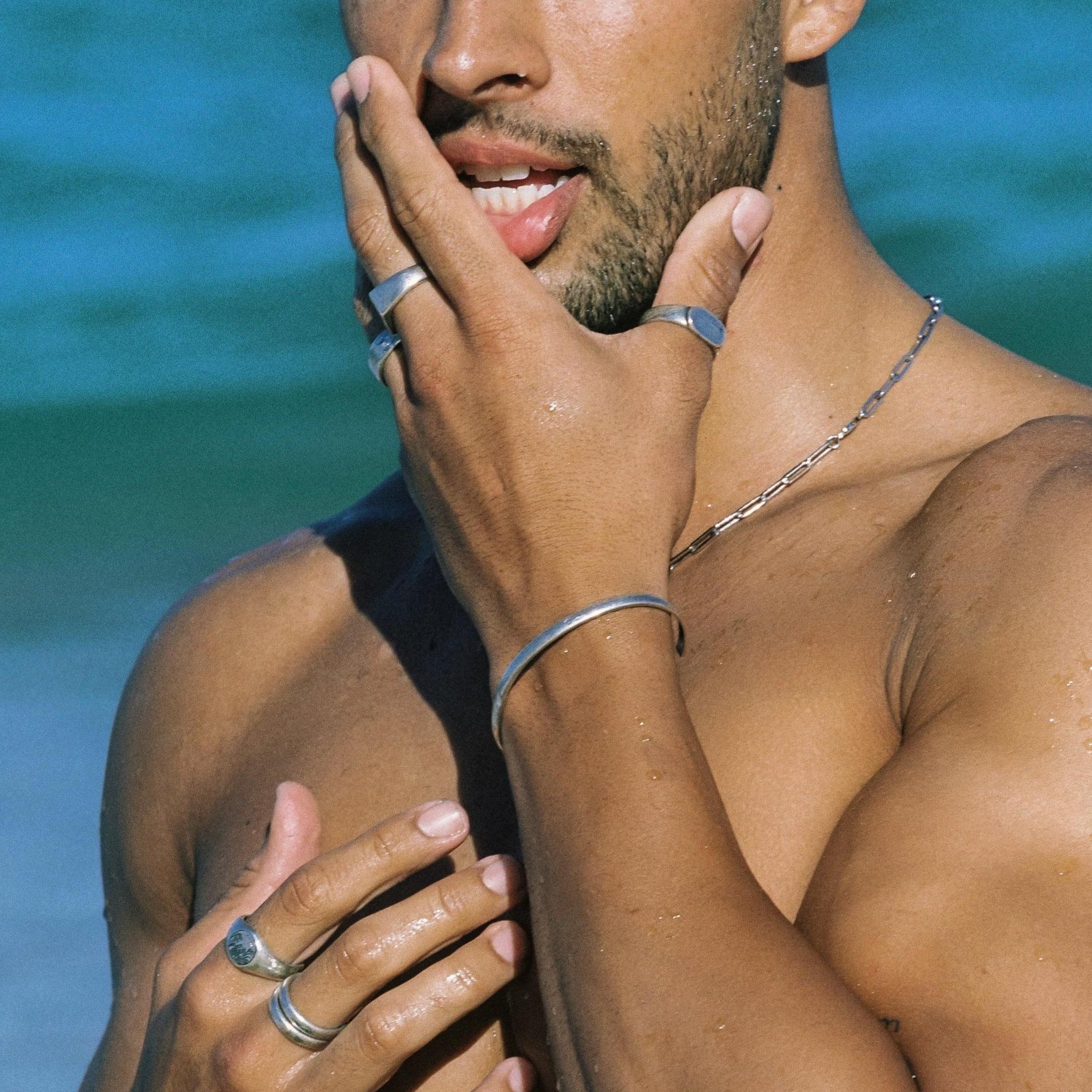 A close-up lifestyle image of a man at the beach wearing the sterling silver Drifter Cuff by Billie Jo, paired with a silver chain and rings.