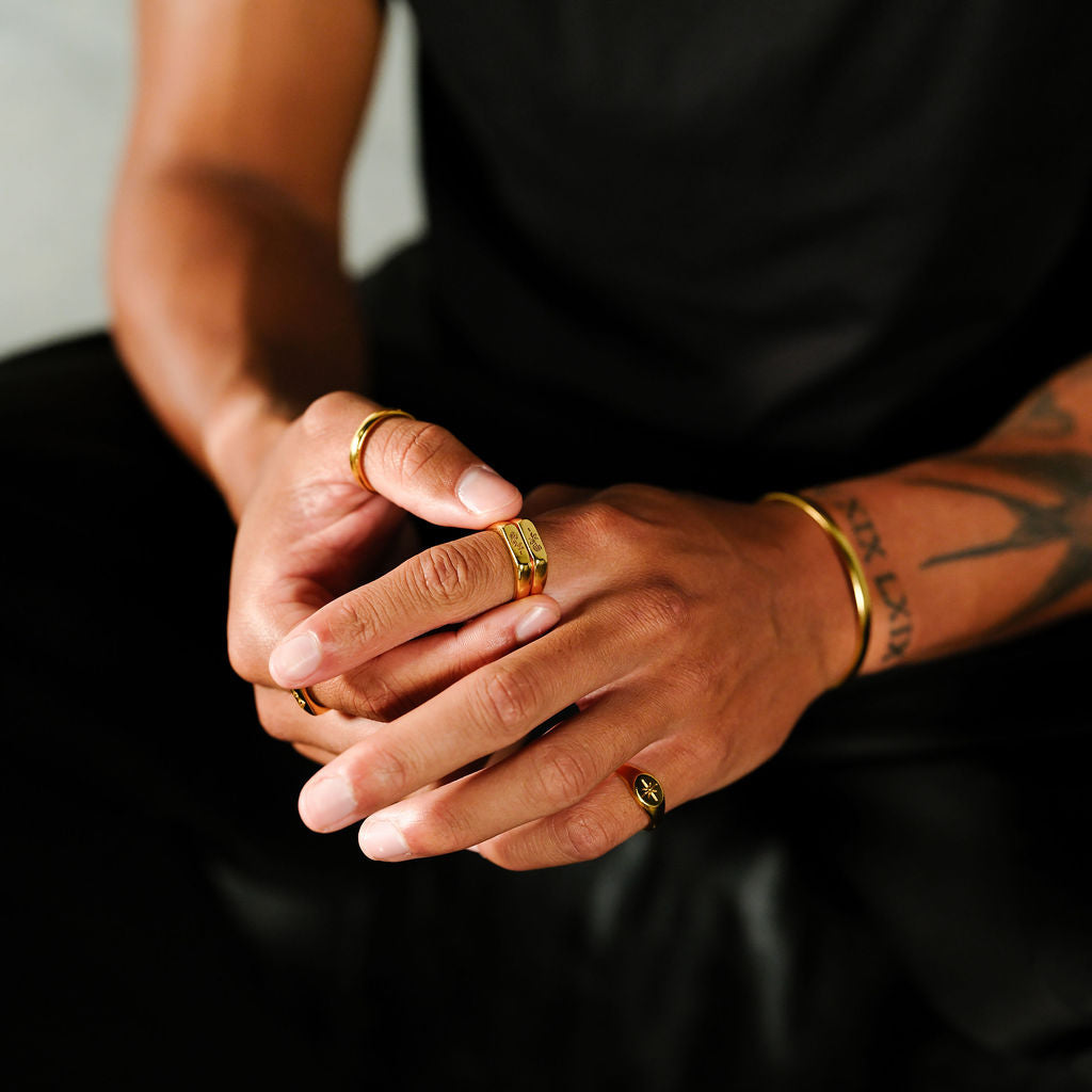 A man wearing the gold Rosa Stacker rings from Australian jewellery brand Billie Jo, with his hands clasped, showing a modern and masculine style.