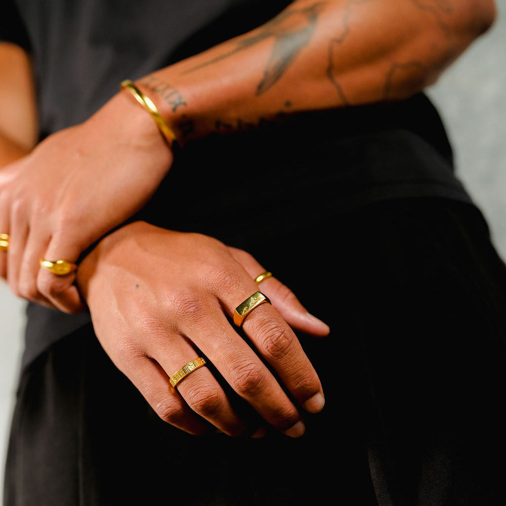 A stylish man wearing multiple gold rings from Billie Jo, with the Union Ring prominently featured, showcasing a modern, layered jewellery look.