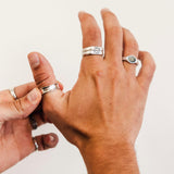 A man's hands putting on the sterling silver Forge Ring by Billie Jo, shown against a clean white background to highlight the ring's unique design.