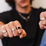 A man wearing the sterling silver Onyx Ring from Billie Jo, shown with other rings on his fists.