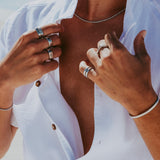 A man wears the sterling silver Rope Necklace by Billie Jo with an open white shirt, layered with silver rings for a stylish, modern look.