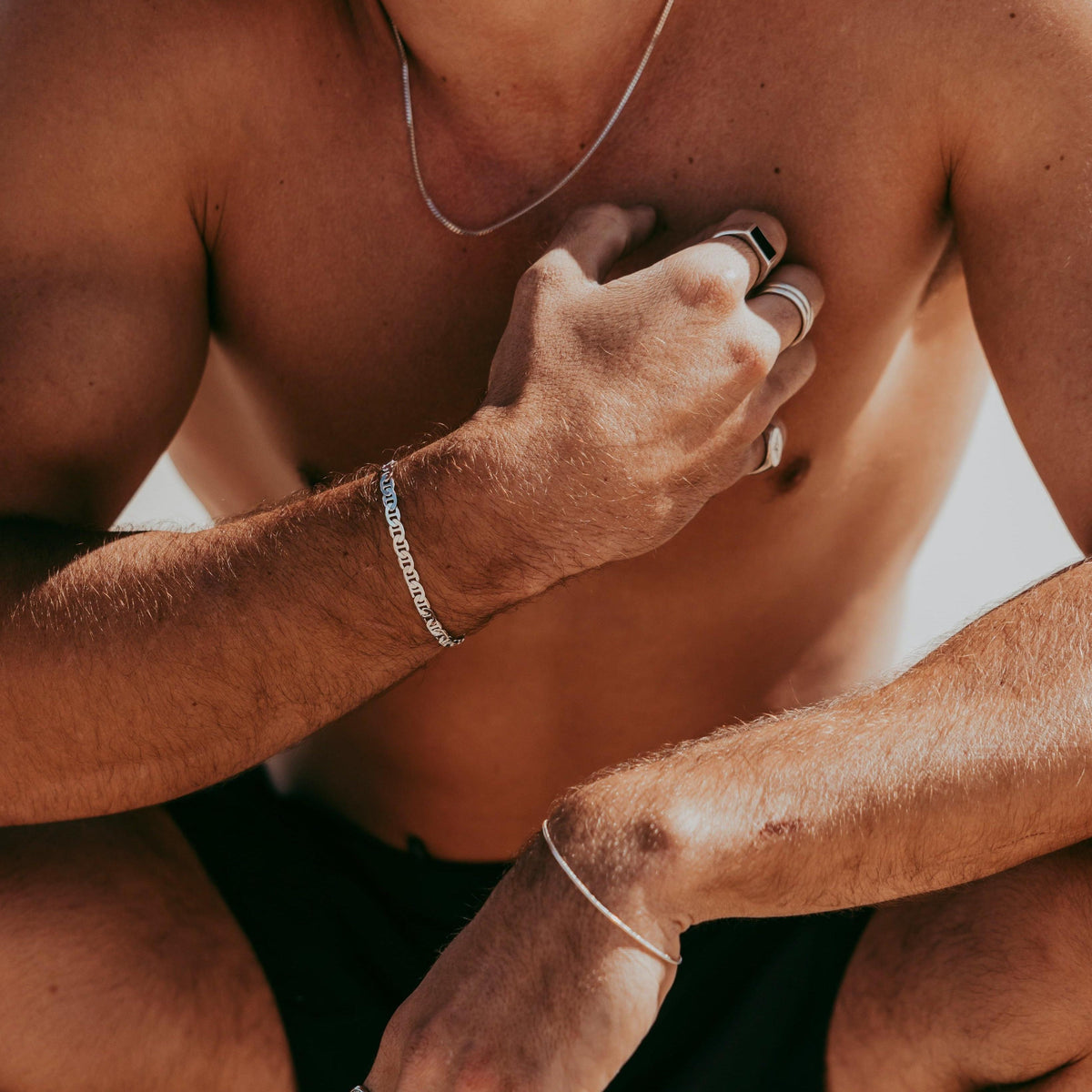 A man wears the sterling silver Curb Necklace by Billie Jo, styled with multiple silver rings and bracelets for a modern, layered jewellery look.