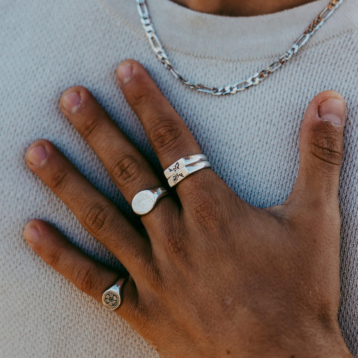 Close-up of the Billie Jo Figaro Necklace in sterling silver, layered over a textured knit. Styled with a selection of the brand's silver rings for a complete look.