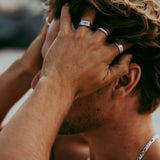 A man running his hands through his hair, showing off his Billie Jo sterling silver rings, including the distinctive Essence Ring on his index finger.