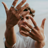 A male model wears a collection of sterling silver rings from Billie Jo, including the Solace Ring. An editorial lifestyle shot showcasing men's jewellery.