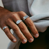 A man's hand wearing the Billie Jo Signet Ring on his index finger, styled with other silver rings for a modern, layered jewellery look.