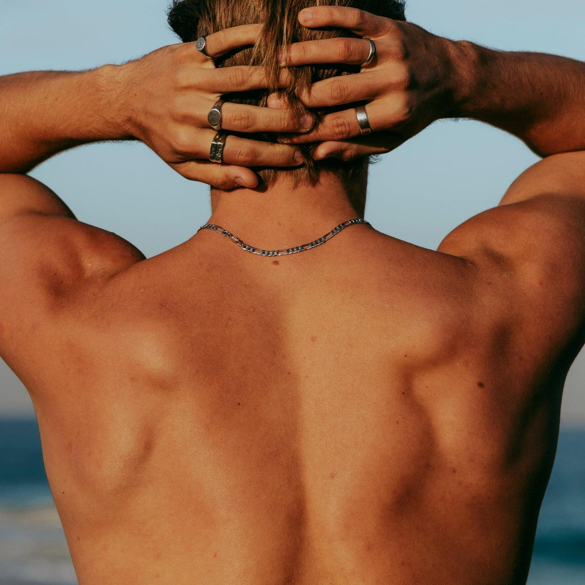 View from behind of a man wearing the sterling silver Figaro Necklace by Billie Jo. A versatile piece of men's jewellery, perfect for a relaxed, beachside look.