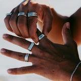 A man with a medium skin tone adjusts the sterling silver Elation Ring on his finger. He wears other silver rings from Australian brand Billie Jo.